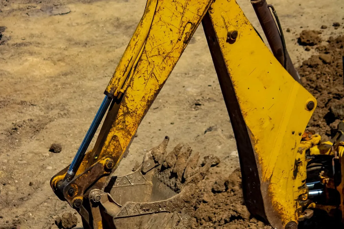 Excavator bucket digging into soil, the kind of excavation done for a new or replacement septic system